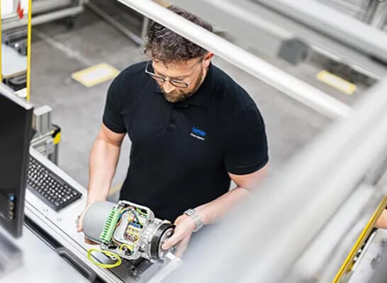 Man holding a motor at a workstation