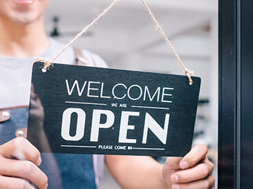 Schild an einer Glast&uuml;r mit der Aufschrift "We are Open"