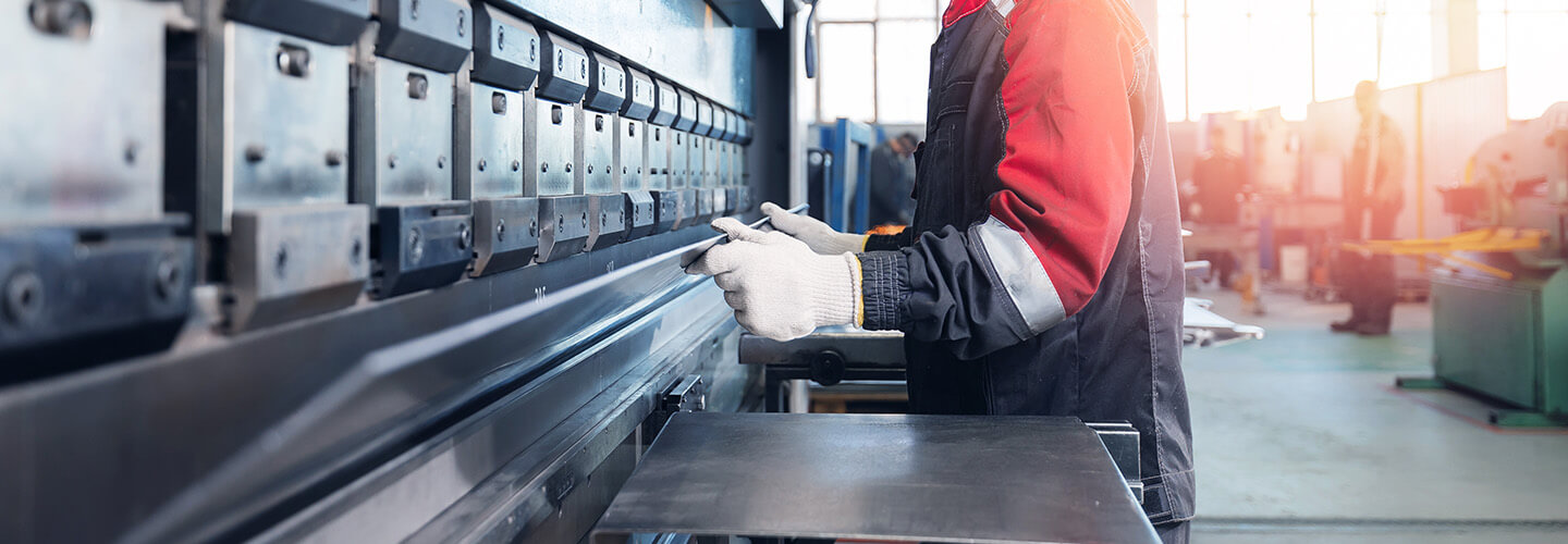 Person steht an einer Maschine und öffnet diese, um daran zu arbeiten