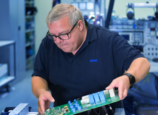 Mann mit Brille untersucht konzentriert eine elektronische Leiterplatte in einer Werkstatt.