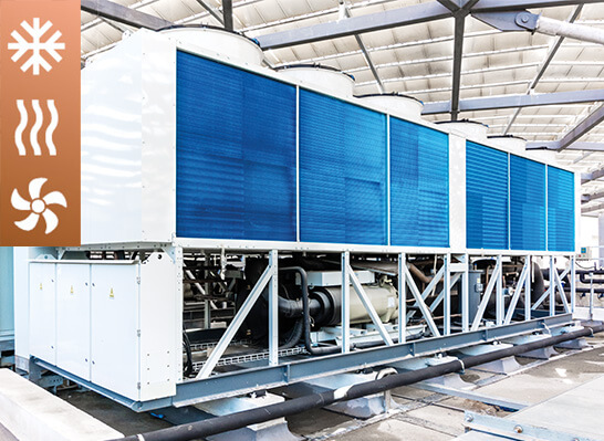 Industrieller Kaltwassersatz mit blauen Wärmetauschern in einer Produktionshalle, verwendet zur Kühlung und Klimatisierung in der Kältetechnik; links Symbole für Kälte, Wärme und Luftstrom.