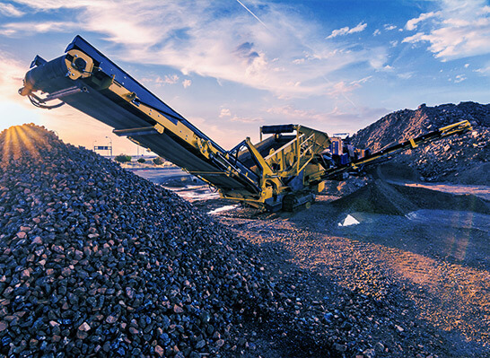 Conveyor belt moves gravel onto a large gravel pile outdoors.