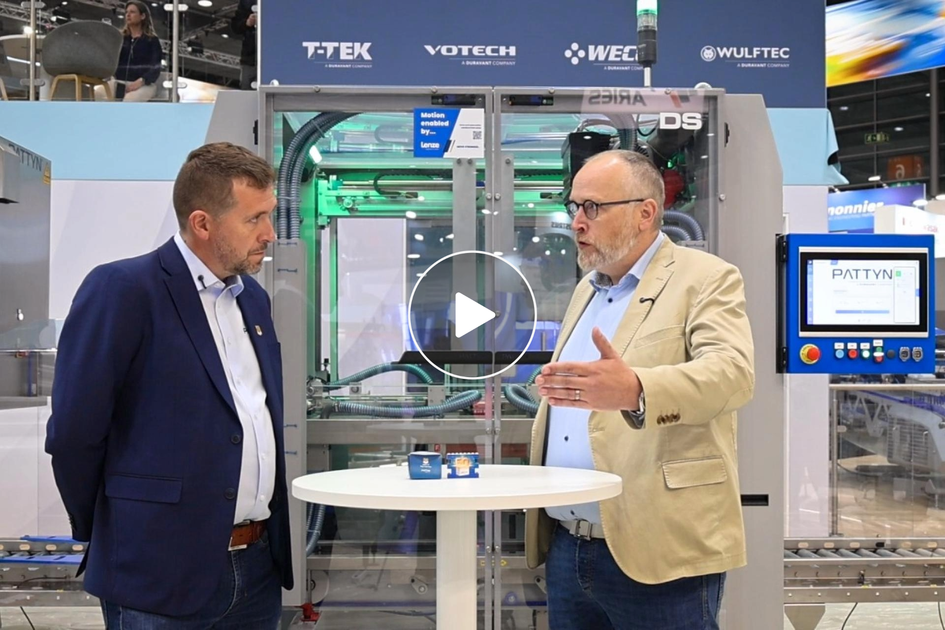Two men talking in front of a machine at a trade fair
